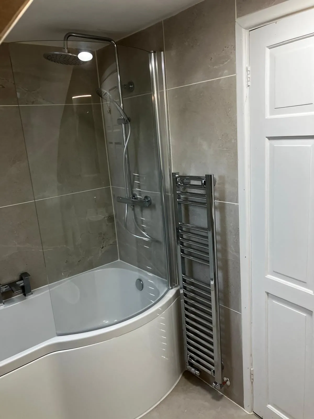 Warm Derby bathroom with a bath, glass shower screen and a heated towel rail