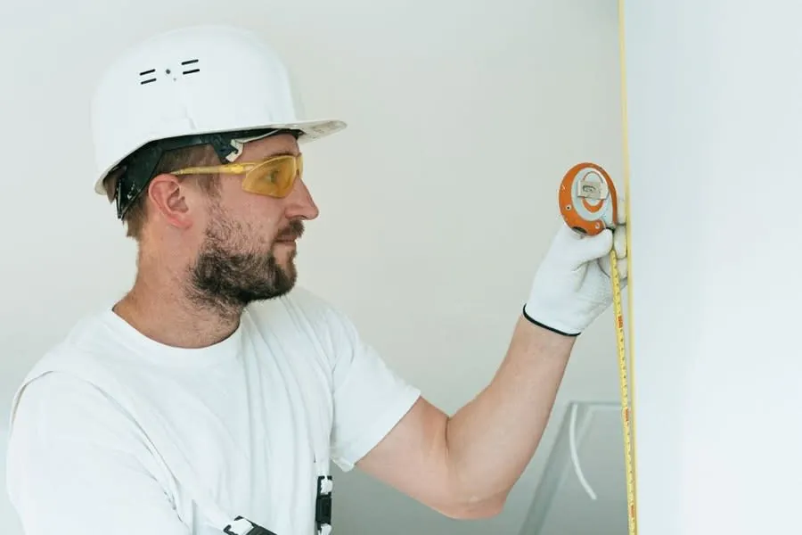Surveyor measuring a wall during a pre-installation check on a Derby bathroom
