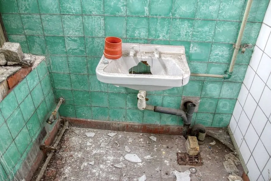 Old bathroom stripped back to bare walls and pipework in a Derby house