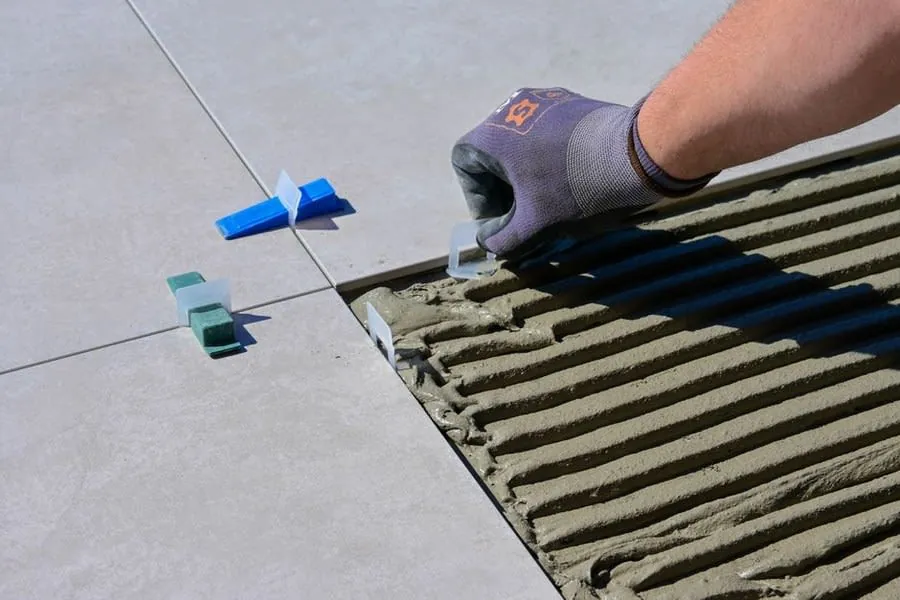 Gloved hand levelling wall tiles during a bathroom installation in Derby