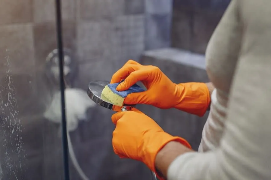 Limescale being cleaned from a shower screen in a hard water Derby home