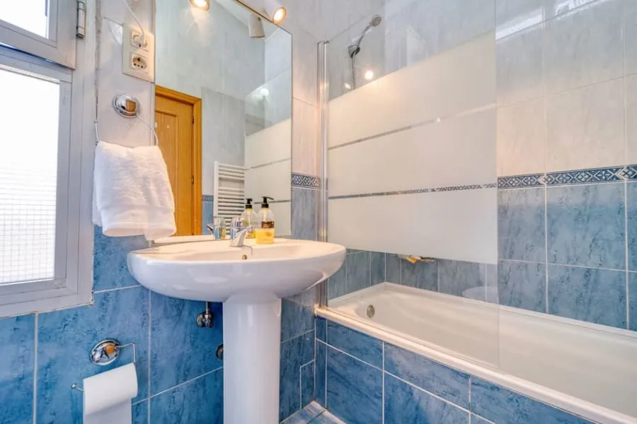 Bathtub with a shower over it and a glass screen in a family bathroom