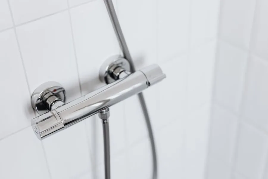 New chrome shower fittings on a tiled bathroom wall after relocation