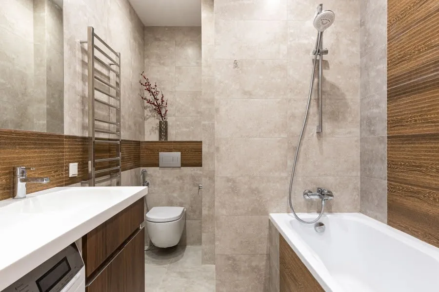 Modern beige bathroom with bathtub, wall-mounted toilet, sink, and shower.