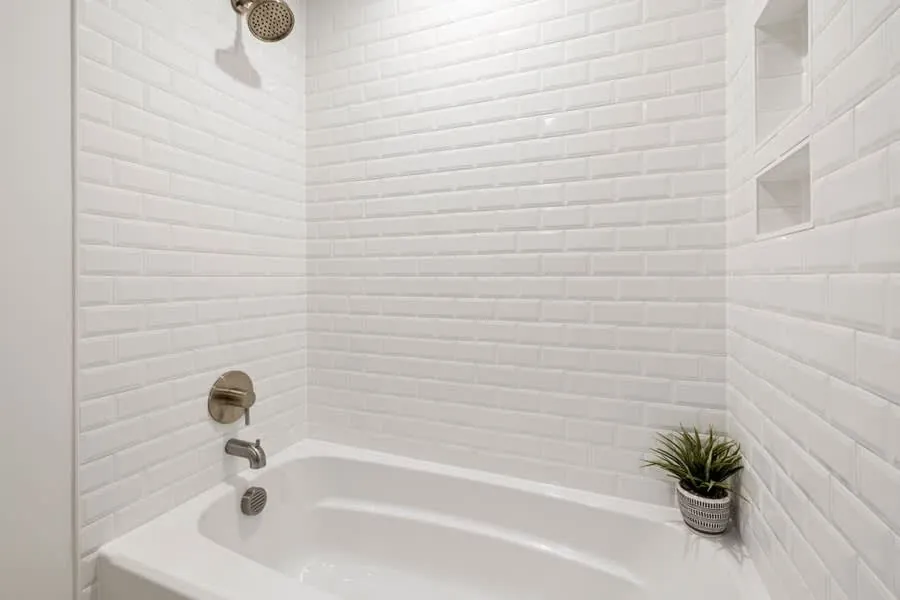 Steel enamel bath against white tiles in a compact bathroom