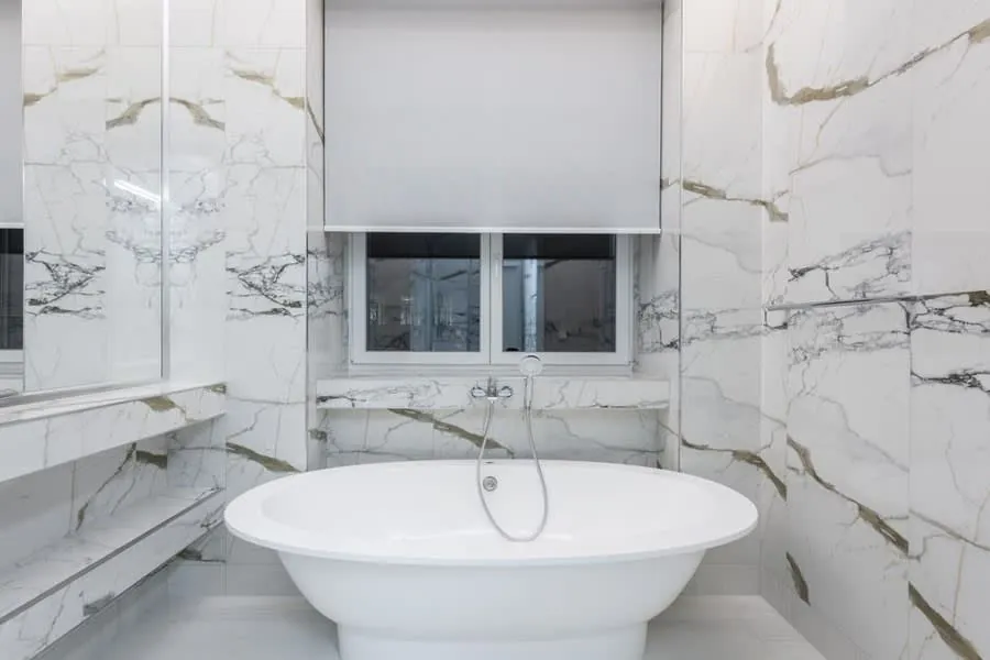Freestanding stone resin bath in a marble-tiled bathroom