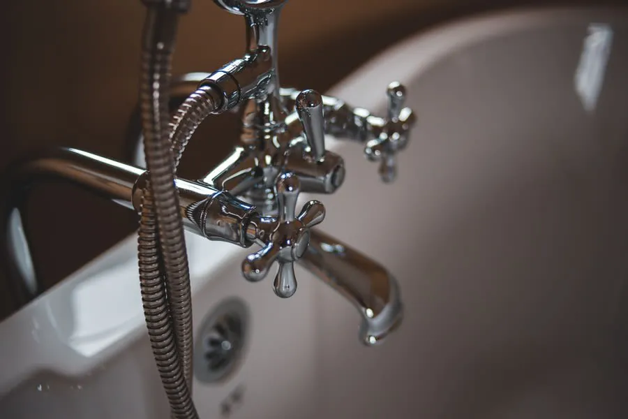 Chrome faucet over a white bathroom sink with running water