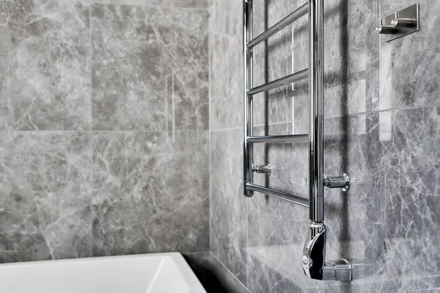 Chrome heated towel rail against a marble-effect bathroom wall in a Derby home