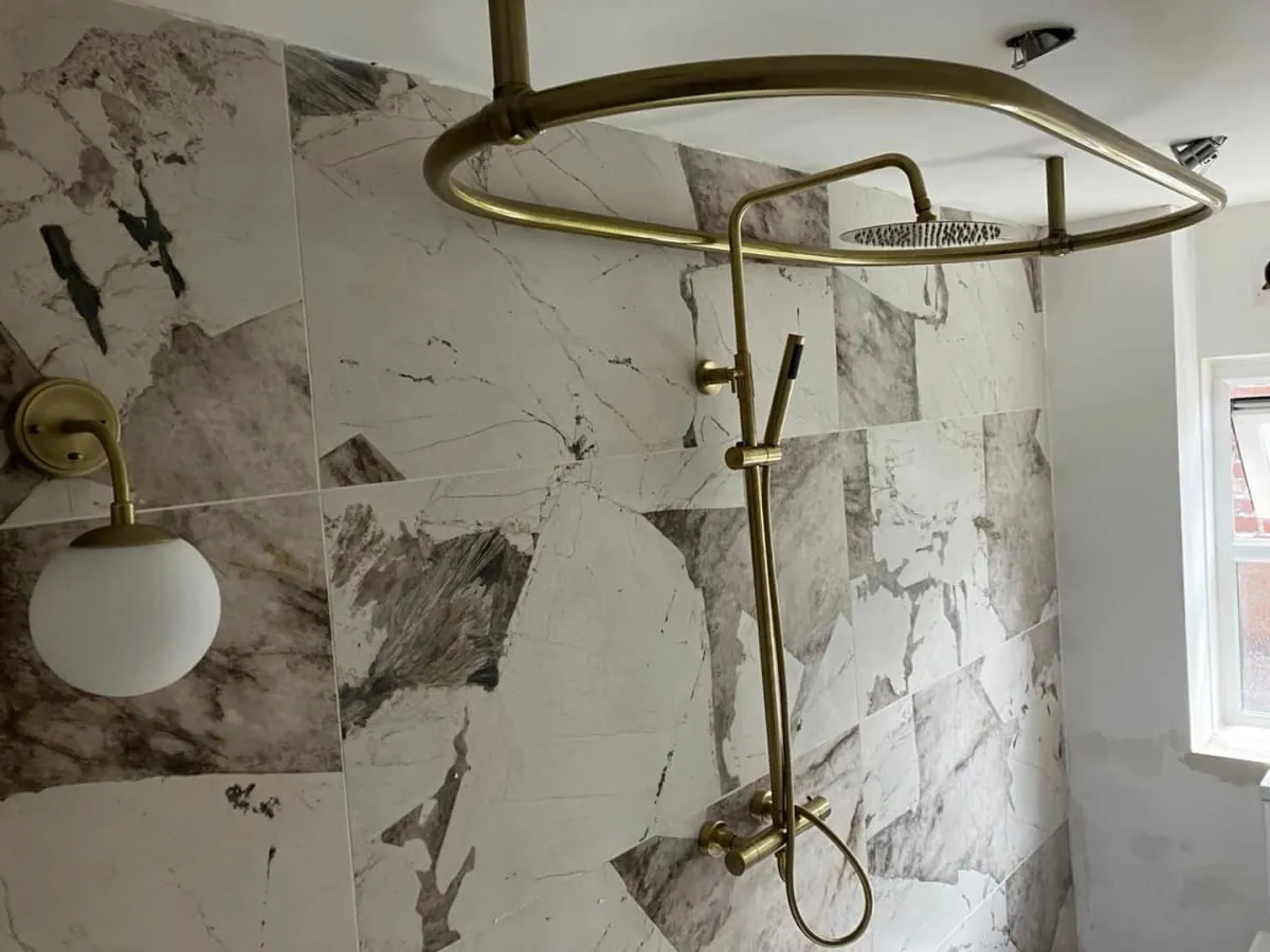 Derby bathroom with marble-patterned tiles and brass shower fixtures