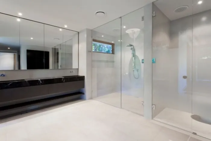 Modern bathroom with a glass shower, black vanity, and large mirror.