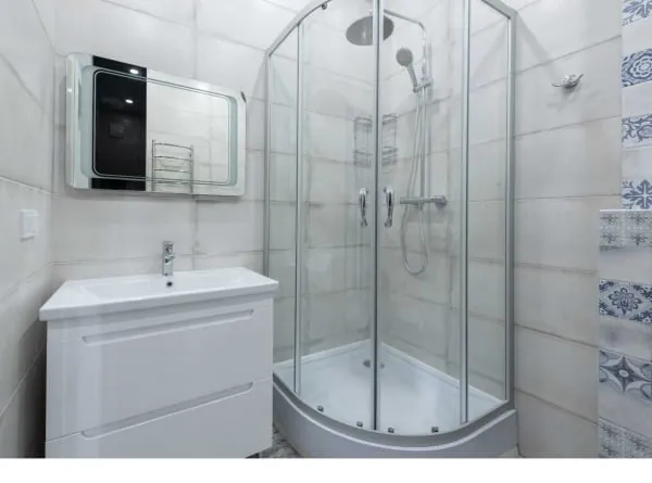 Bathroom with white vanity, glass shower, and tiled walls.