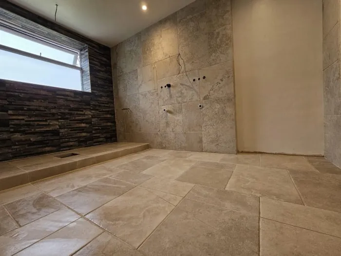 Bathroom with stone tiles, stone accent wall and window with stone surround.