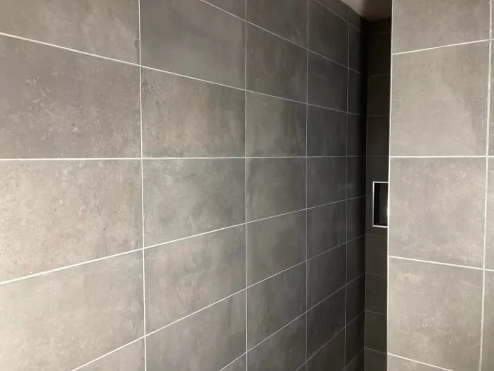 Gray tiled shower with a recessed soap dish.
