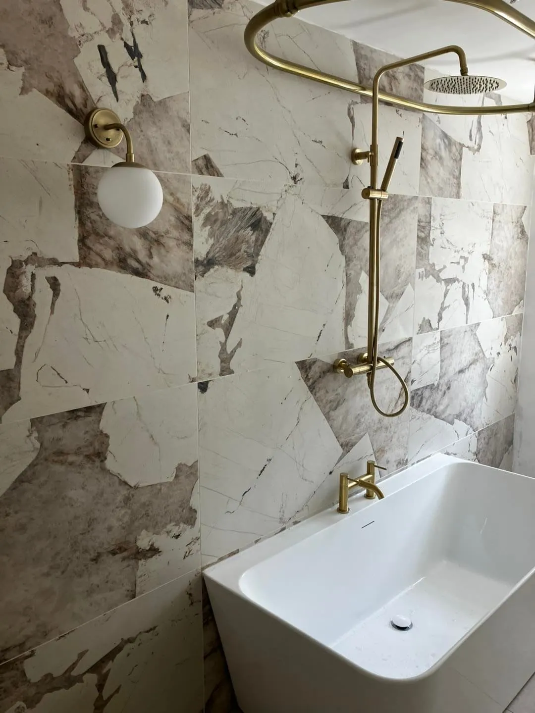 Walk-in shower in a Derby bathroom with marble-effect tiling and a glass screen