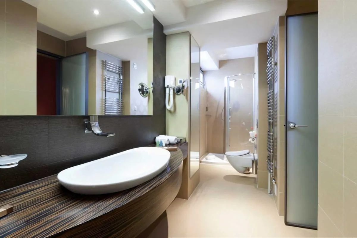 Relocated bathroom in a Derby home with a white sink, large mirror and glass shower