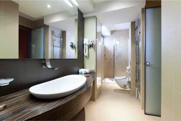 Modern bathroom with a white sink, large mirror, and glass shower.